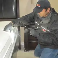 Bed bug inspection technician checking a mattress and bed frame for signs of infestation in Wilmington, NC