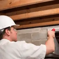 Termite inspection technician checking a basement wall and framing for termite activity in Wilmington, NC