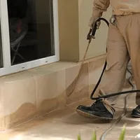 General pest control technician spraying exterior perimeter around a home in Wilmington, NC